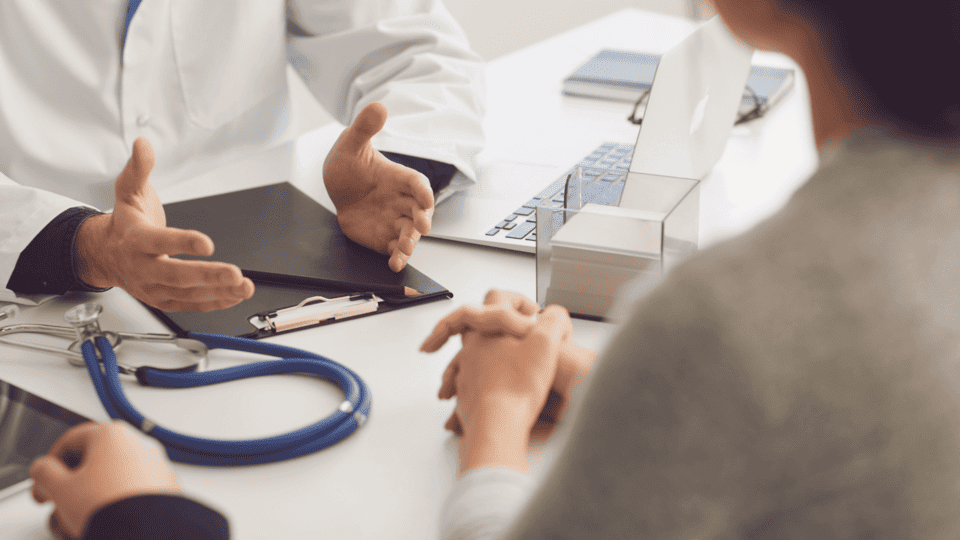 Médico conversando con paciente adolescente en consulta de salud preventiva