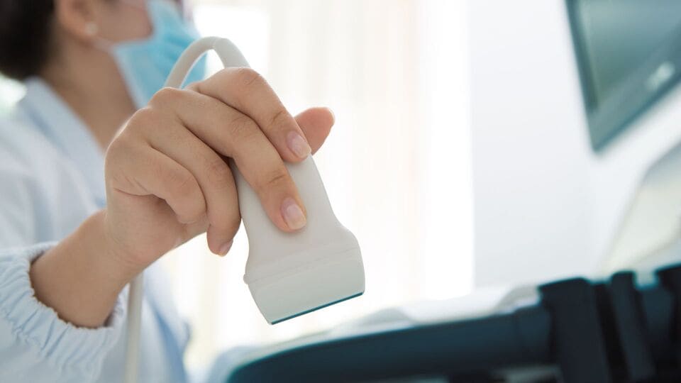 Médico realizando evaluación con transductor durante una ecografía mamaria