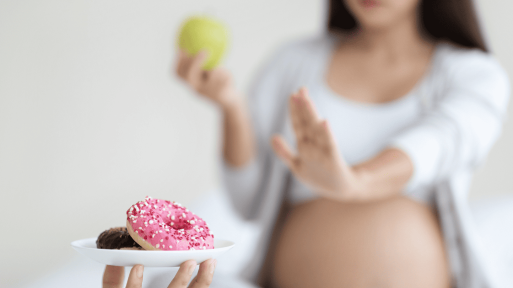 Mujer embarazada rechazando donas mientras sostiene una manzana en la mano